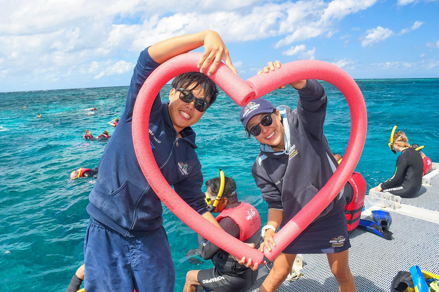 Down Under Cruise and Dive crew members with pool noodles in the shape of a heart on the reef